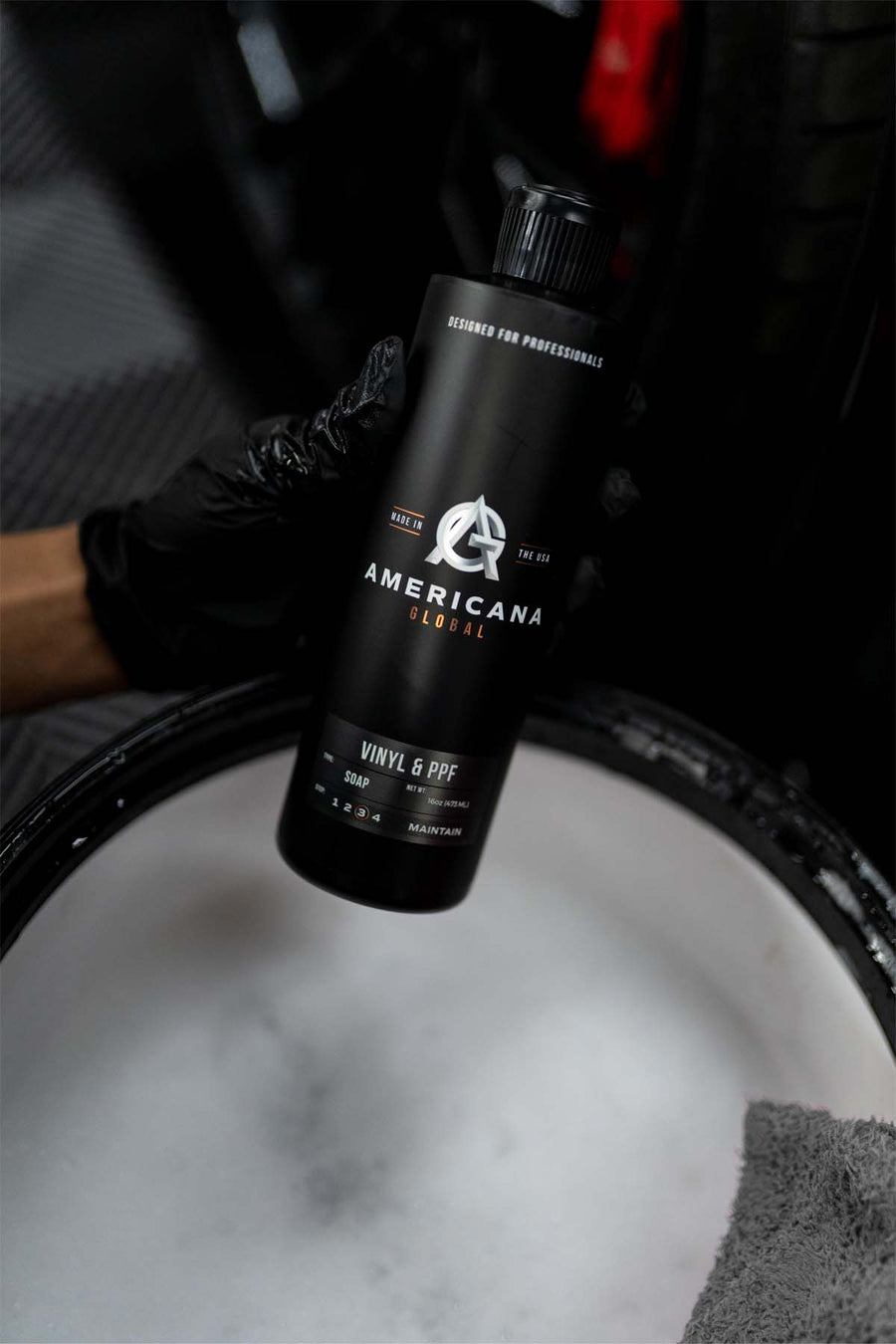 Americana Global maintenance product held over a foam-filled wash bucket